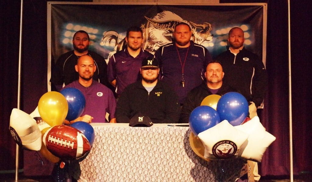 Garrett Sellers is seated with Gilmer County football coaches. Sellers commited to playing college football for Navy during National College Signing Day yesterday. (Photo by: Kevin Hensley)