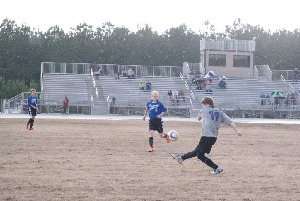 Clear Creek Bobcat Alex Snelgrove punts the ball away yesterday against Fannin, as Rebel Cohutta Hyde scrambles to intercept. Snelgrove and Hyde scored one goal each in the first half of a match that ended in a 2-2 tie. (Photo by: Kevin Hensley)